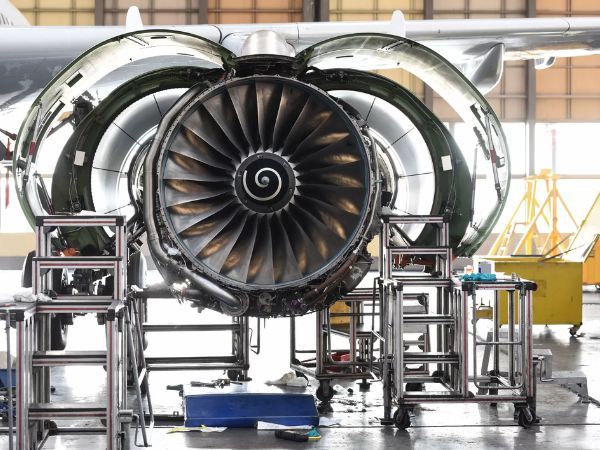 Aircraft engine assembly in an aerospace maintenance facility showing a large turbofan engine during inspection and servicing