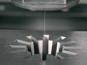 Wire EDM cutting metal part with a precision electrode wire for additive manufacturing post processing